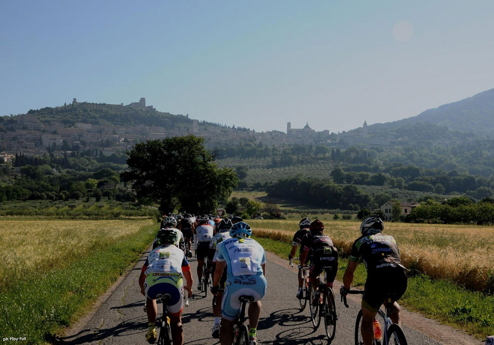 ciclisti-con-assisi-in-lontananza